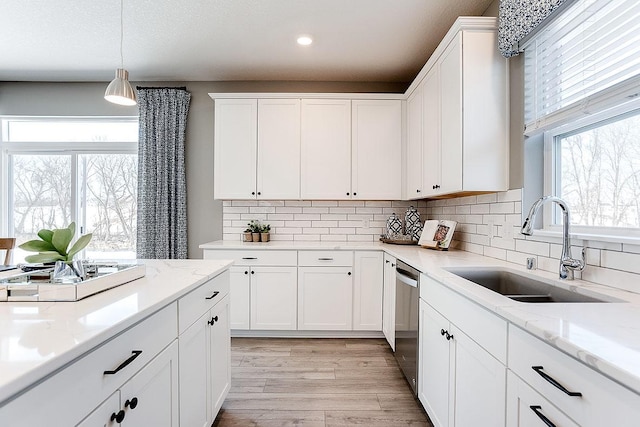 kitchen with white cabinetry, sink, decorative light fixtures, and light wood-type flooring