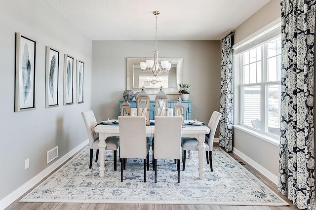 dining space with hardwood / wood-style floors, an inviting chandelier, and a wealth of natural light