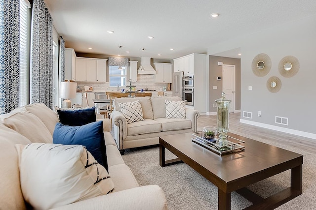 living room featuring recessed lighting, light wood-style floors, visible vents, and baseboards