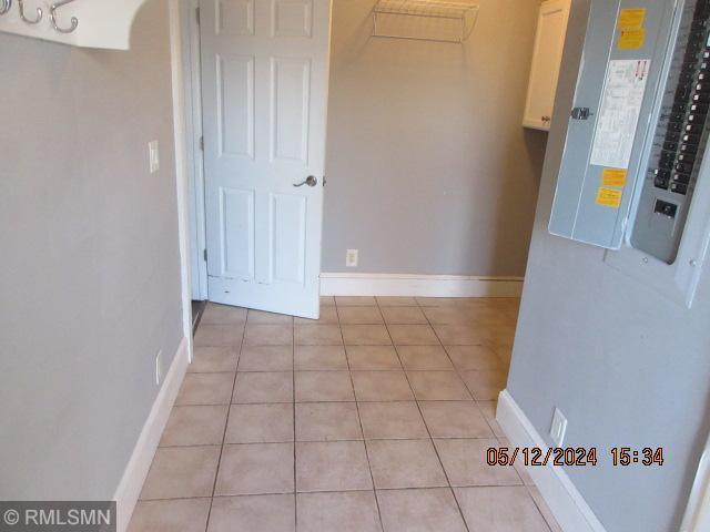 corridor with light tile patterned flooring and electric panel