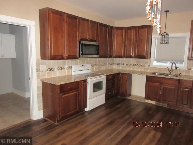 kitchen with sink, dark hardwood / wood-style floors, pendant lighting, electric stove, and decorative backsplash