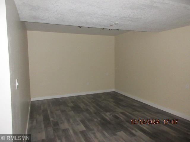 unfurnished room with a textured ceiling and dark wood-type flooring