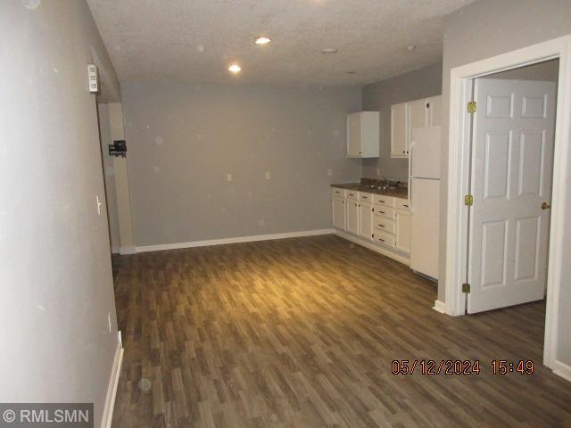 interior space featuring white cabinets, dark hardwood / wood-style flooring, white fridge, and a textured ceiling