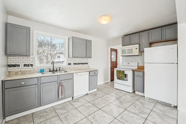 kitchen featuring gray cabinetry, sink, white appliances, and backsplash