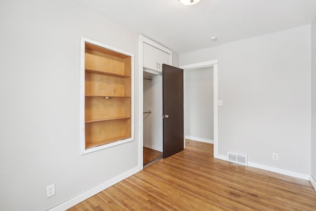 unfurnished room with built in features and light hardwood / wood-style floors