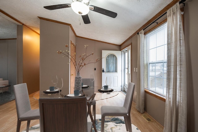 dining room featuring a textured ceiling, lofted ceiling, ornamental molding, and light hardwood / wood-style flooring