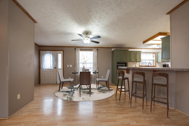 dining room featuring a wealth of natural light, ornamental molding, a textured ceiling, and light wood-type flooring