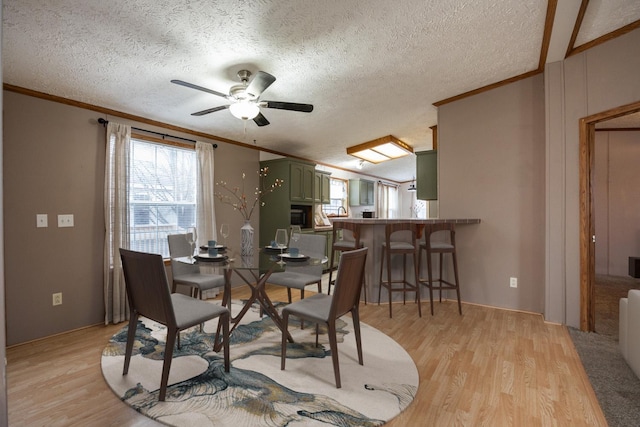 dining space with ceiling fan, light hardwood / wood-style floors, a textured ceiling, and ornamental molding