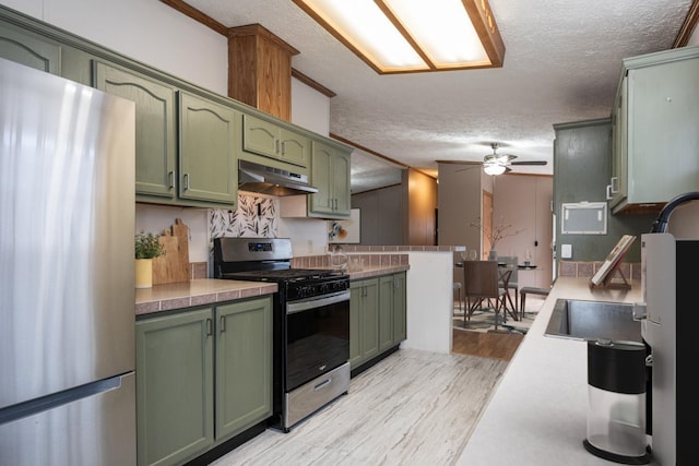 kitchen featuring green cabinets, stainless steel appliances, a textured ceiling, and light hardwood / wood-style floors