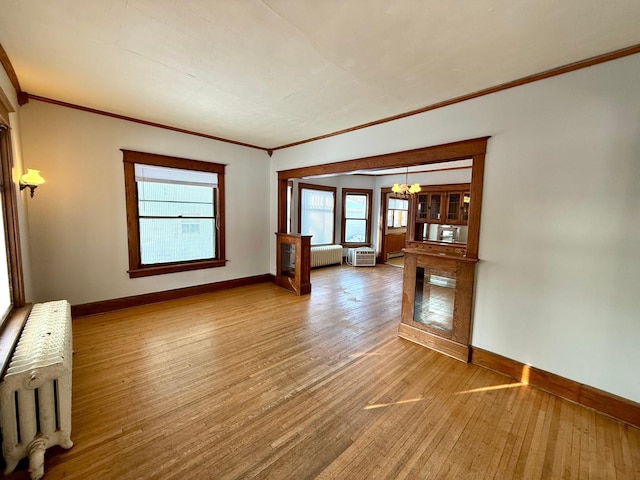 spare room featuring a chandelier, radiator heating unit, and hardwood / wood-style flooring