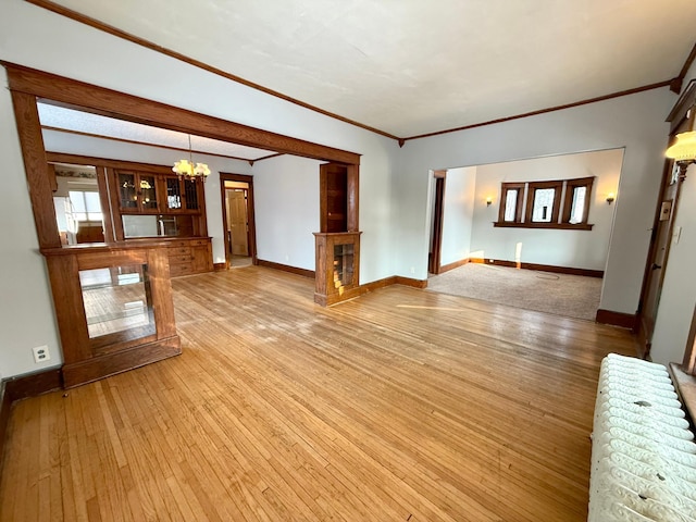 unfurnished living room with crown molding, hardwood / wood-style floors, and a chandelier