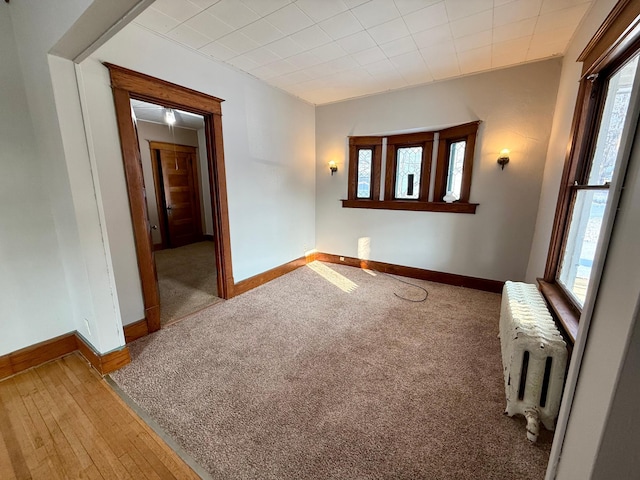 carpeted spare room with a wealth of natural light and radiator heating unit