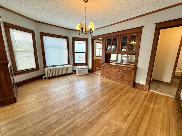 unfurnished dining area with light wood-type flooring, radiator, a textured ceiling, an AC wall unit, and a chandelier