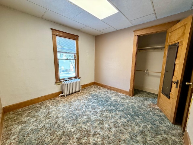 unfurnished bedroom featuring radiator heating unit, dark carpet, and a closet