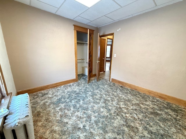 empty room featuring carpet and a drop ceiling