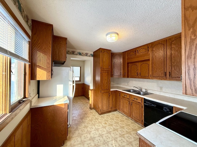 kitchen with dishwasher, wood walls, white refrigerator, sink, and a textured ceiling