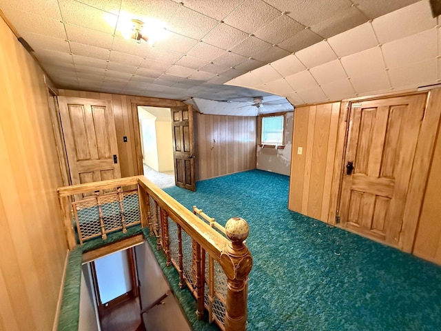 bonus room with carpet floors and wood walls