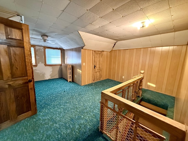 additional living space with carpet flooring, ceiling fan, wood walls, and radiator