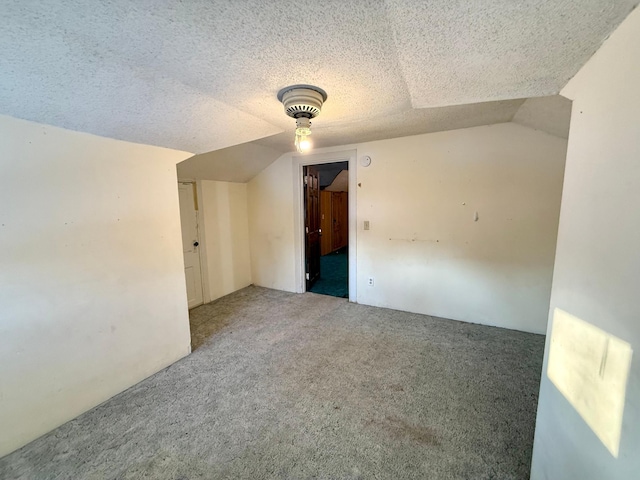 empty room with carpet, a textured ceiling, and vaulted ceiling