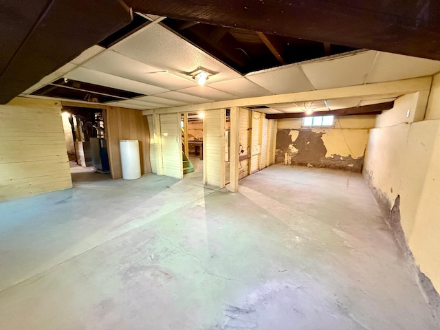 basement with wood walls and water heater