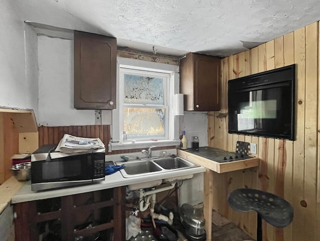 kitchen featuring wood walls, sink, and a textured ceiling