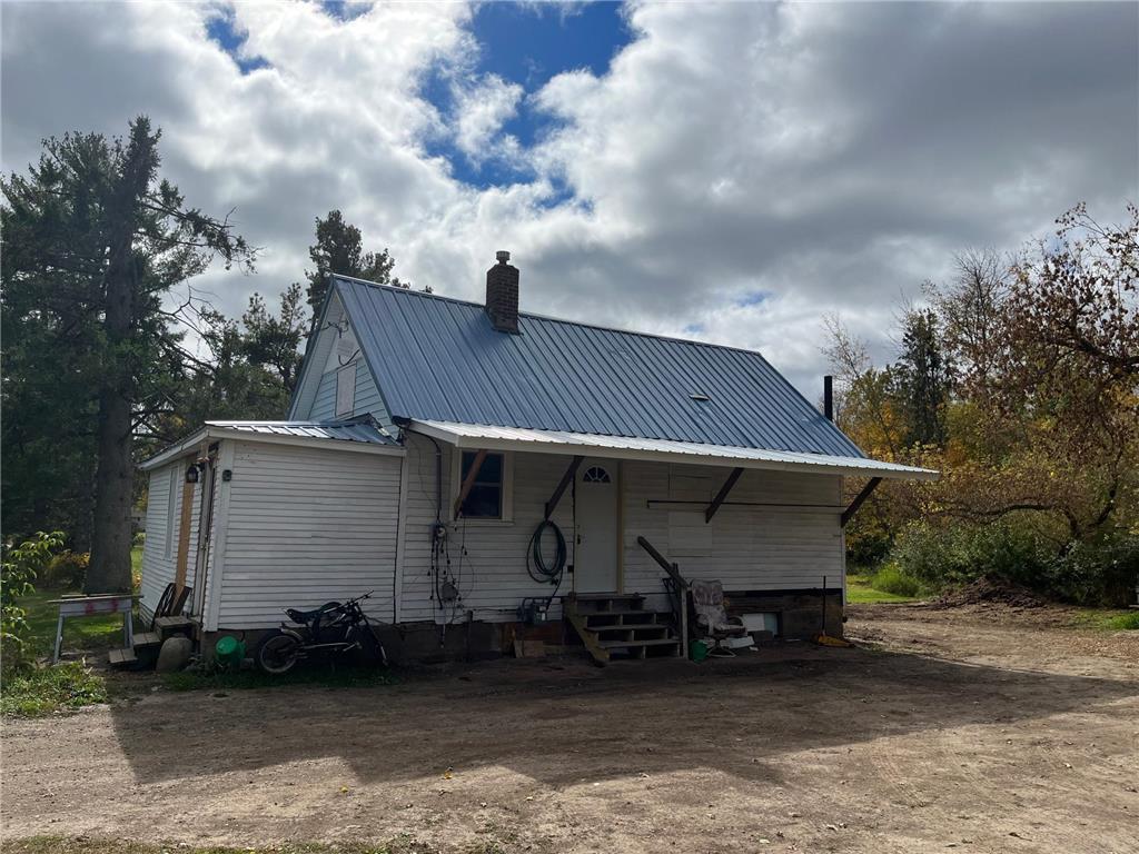 back of house with entry steps, a chimney, and metal roof