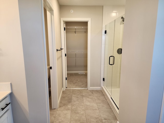 bathroom featuring a shower with shower door and vanity