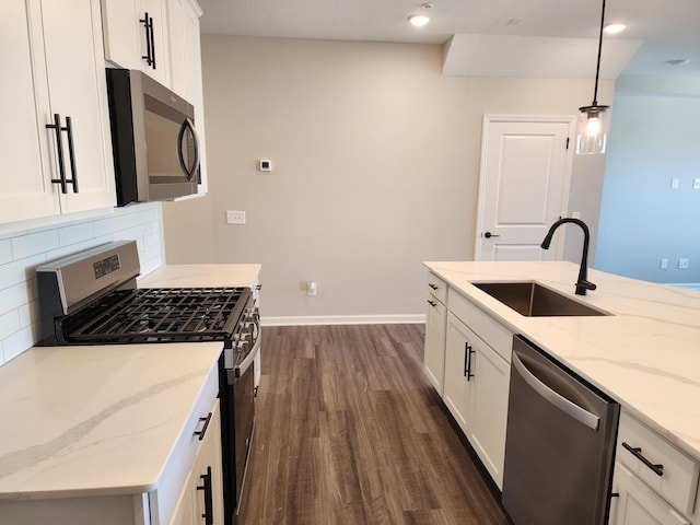 kitchen featuring light stone countertops, white cabinets, decorative light fixtures, stainless steel appliances, and sink