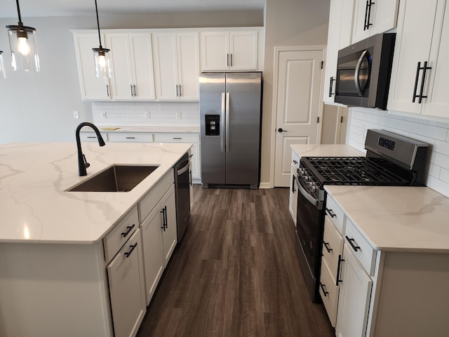 kitchen featuring stainless steel appliances, sink, white cabinetry, and decorative light fixtures