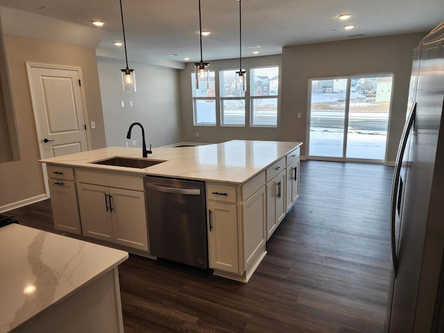 kitchen featuring white cabinets, stainless steel appliances, sink, hanging light fixtures, and a kitchen island with sink