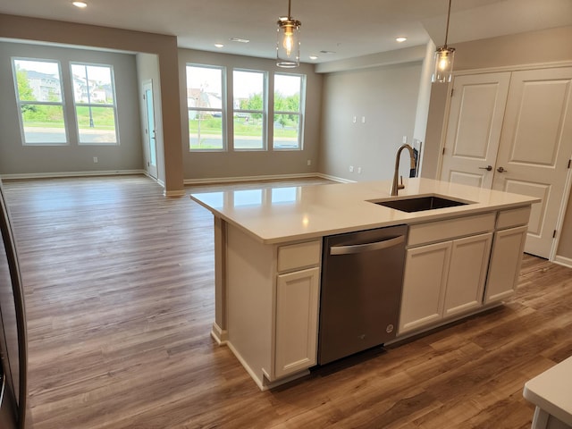 kitchen with stainless steel dishwasher, pendant lighting, a center island with sink, and a wealth of natural light