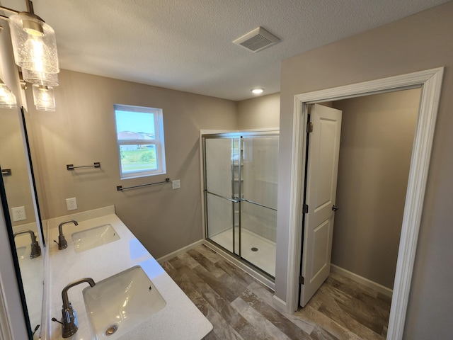 bathroom with hardwood / wood-style floors, vanity, a shower with door, and a textured ceiling