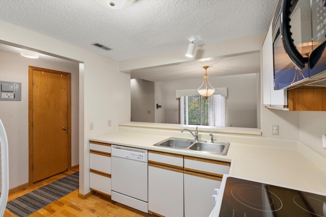 kitchen with white cabinetry, dishwasher, sink, decorative light fixtures, and light wood-type flooring