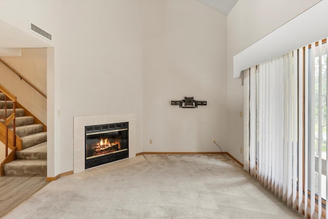 unfurnished living room with a fireplace, a towering ceiling, and carpet floors