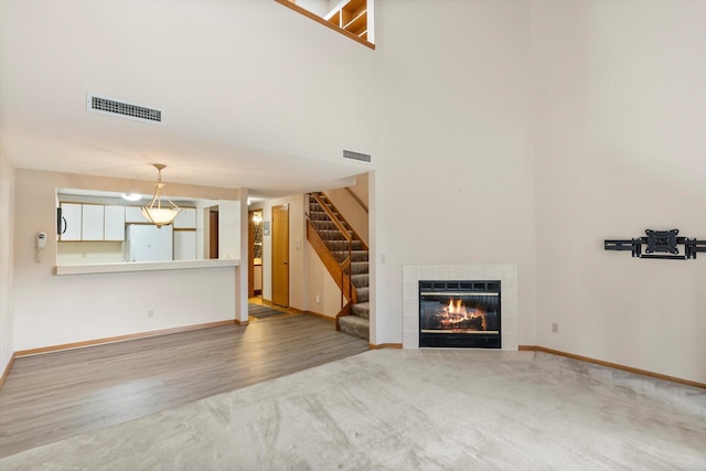 unfurnished living room with hardwood / wood-style floors, a fireplace, and a high ceiling