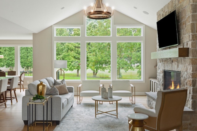 living room featuring a fireplace, high vaulted ceiling, an inviting chandelier, and light wood-type flooring