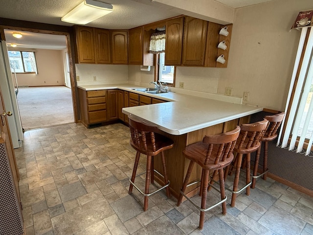 kitchen with kitchen peninsula, light carpet, a breakfast bar, sink, and white refrigerator