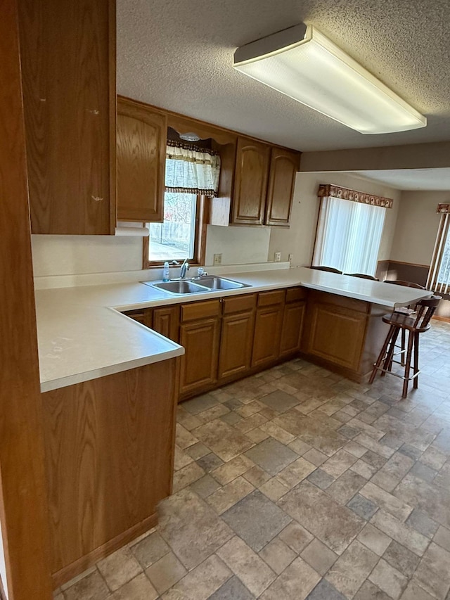 kitchen with kitchen peninsula, a kitchen breakfast bar, a textured ceiling, and sink