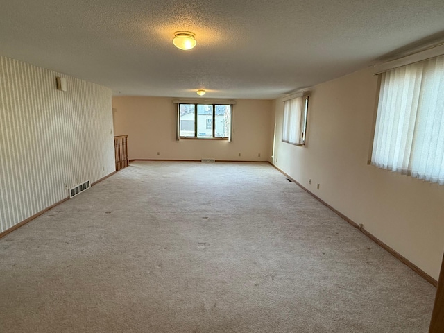 carpeted empty room featuring a textured ceiling