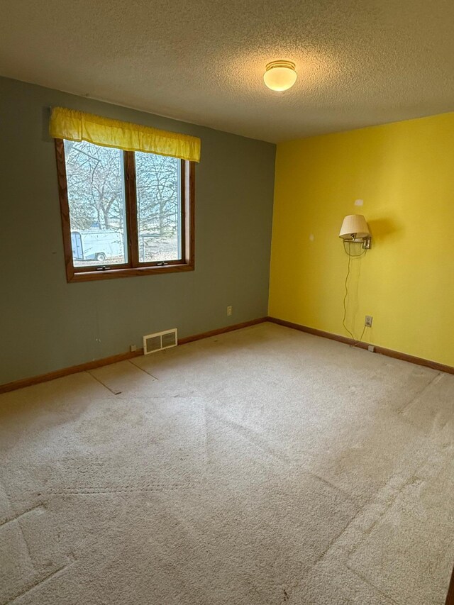 carpeted spare room featuring a textured ceiling