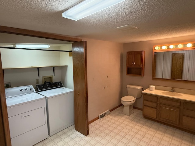 bathroom with vanity, a textured ceiling, separate washer and dryer, and toilet