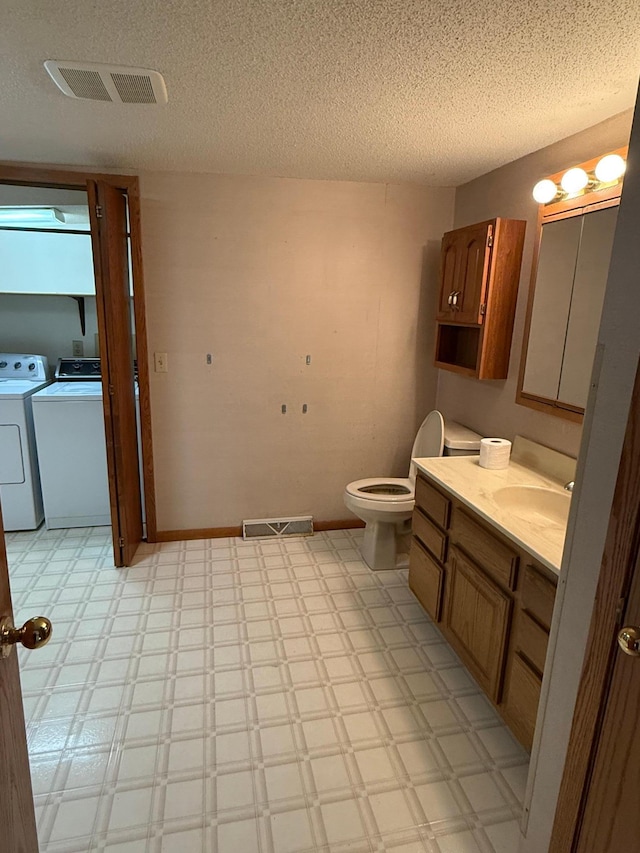 bathroom with vanity, a textured ceiling, separate washer and dryer, and toilet