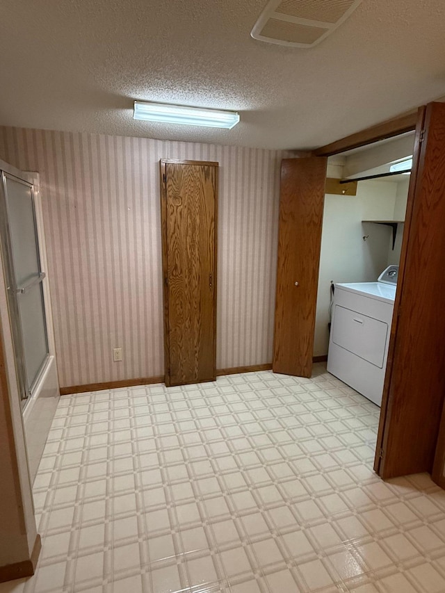 clothes washing area featuring a textured ceiling and washer / dryer