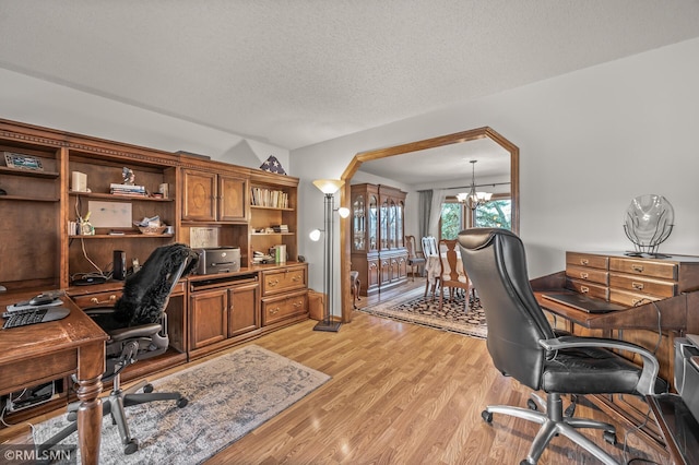 office area featuring a textured ceiling, light hardwood / wood-style flooring, and an inviting chandelier