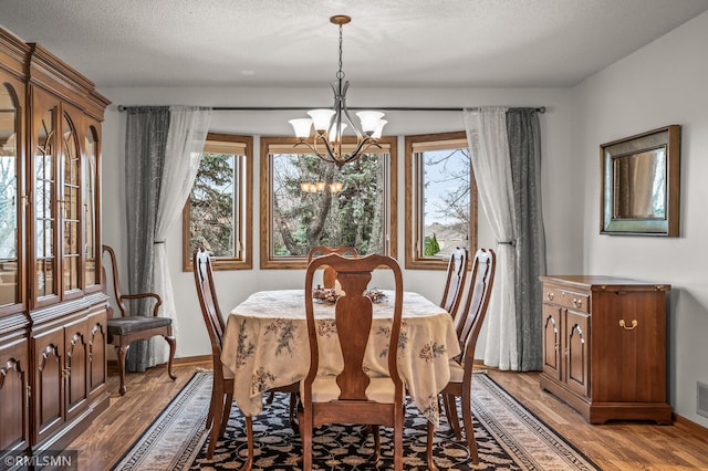 dining space with a chandelier, light hardwood / wood-style flooring, a healthy amount of sunlight, and a textured ceiling