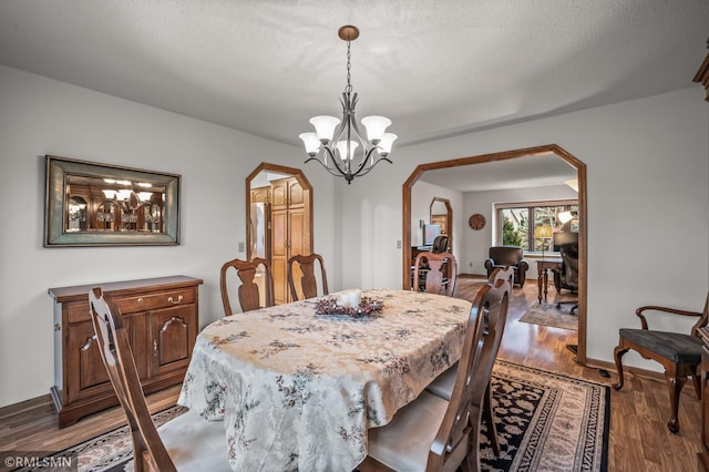 dining area featuring a textured ceiling, hardwood / wood-style flooring, and a notable chandelier