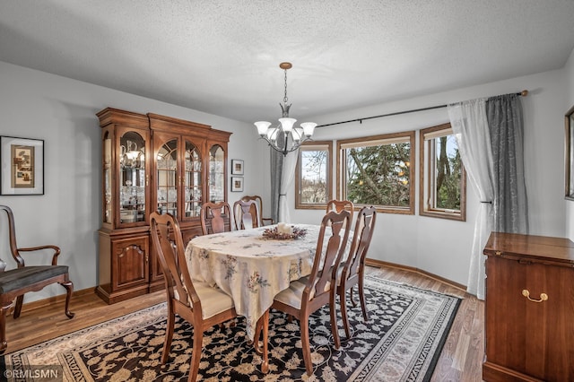 dining room with hardwood / wood-style floors, a textured ceiling, and an inviting chandelier