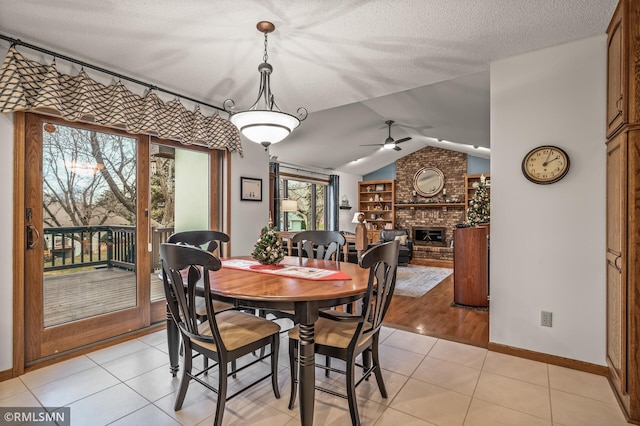 dining area with ceiling fan, light tile patterned floors, a textured ceiling, and lofted ceiling