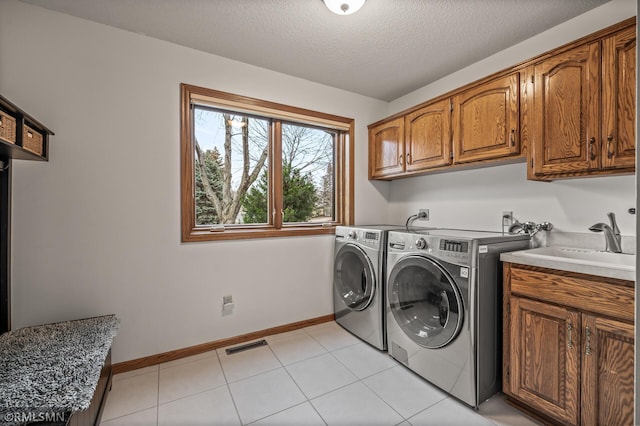 laundry room featuring cabinets, a textured ceiling, separate washer and dryer, and light tile patterned flooring