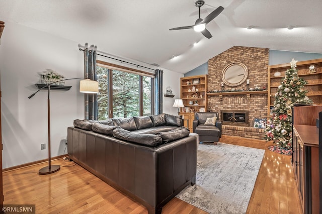 living room featuring ceiling fan, a brick fireplace, light hardwood / wood-style floors, a textured ceiling, and vaulted ceiling